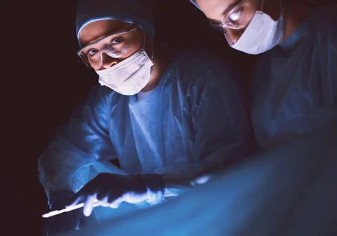 Doctors team in surgery in a dark background. Stock Photos
