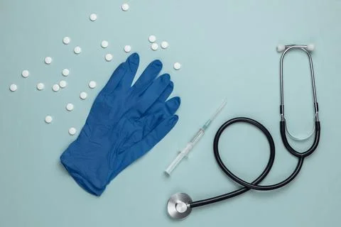 Doctor's tools on a blue background. Gloves, syringe, stethoscope and pills.  Stockfoto's