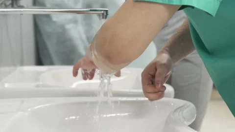 Doctors wash their hands under water and soap before undergoing surgery Stock Footage 156194932