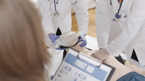 Doctors in white lab coats and blue gloves performing first aid on dummy 스톡 동영상 270174728