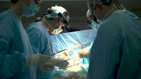 Doctors work in the operating room. A nurse and an assistant hand over the Stock Footage 277518575