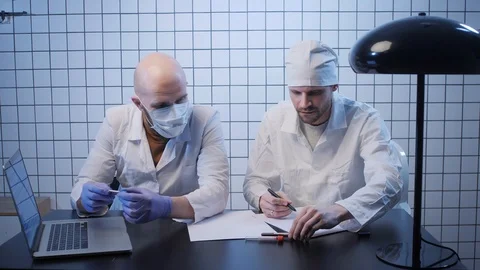 Doctors work with sample of coronavirus in tube at table Video stock 126952440