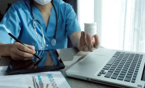 Doctor's working on laptop computer, writing prescription clipboard with re.. Stock Photos