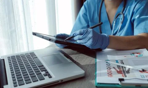 Doctor's working on laptop computer, writing prescription clipboard with re.. Stock Photos