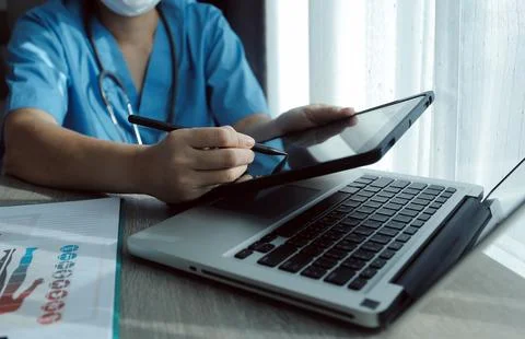 Doctor's working on laptop computer, writing prescription clipboard with re.. Stock Photos