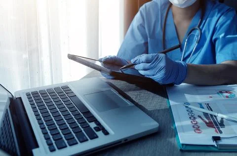 Doctor's working on laptop computer, writing prescription clipboard with re.. Stock Photos