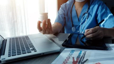 Doctor's working on laptop computer, writing prescription clipboard with re.. Stock Photos