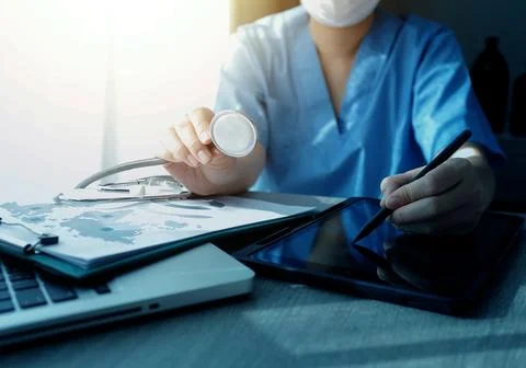 Doctor's working on laptop computer, writing prescription clipboard with re.. Stock Photos