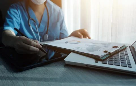 Doctor's working on laptop computer, writing prescription clipboard with re.. Foto stock