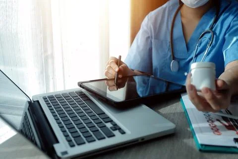 Doctor's working on laptop computer, writing prescription clipboard with re.. Stock Photos