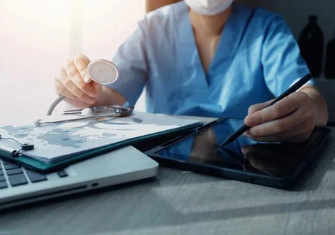 Doctor's working on laptop computer, writing prescription clipboard with re.. Stock Photos