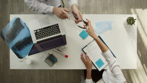 Doctors working together top view. Woman nurse giving stethoscope to man Stock Footage 160828323