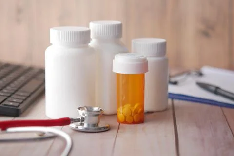 Doctors workplace with container, keyboard and prescription on desk. Stock Photos
