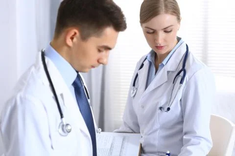 Doctors writing papers using clipboard. Physicians discussing medication program Foto stock