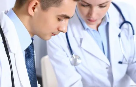 Doctors writing papers using clipboard. Physicians discussing medication program 库存照片