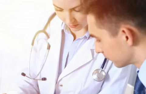 Doctors writing papers using clipboard. Physicians discussing medication program Stockfoto's