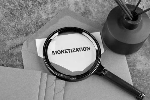 A document labeled monetization is examined closely with a magnifying glass o Stockfoto's