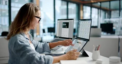 Document Manager Reviews Digital Files Carefully Using Dual Touchscreen Lapto Stock Photos