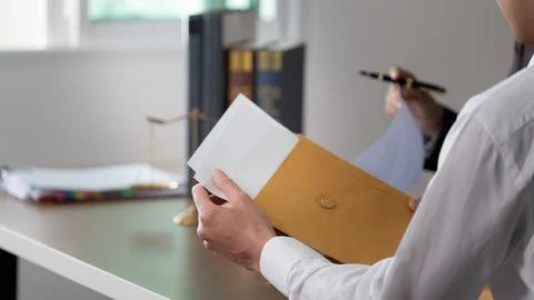 Document Review. A client holding a legal envelope while consulting with a Stock Photos
