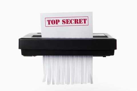A document with TOP SECRET on it being shredded in a paper shredder Stock Photos