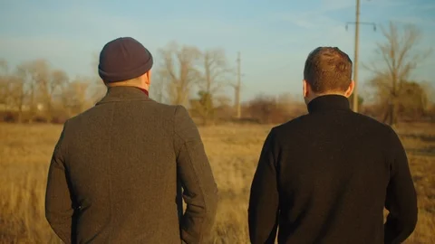 Documentary scene. Two men are walking in the field. The camera follows them. Stock Footage 121613027