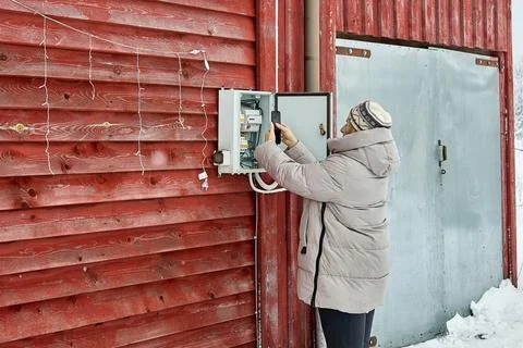 Documenting meter data homeowner in warm winter clothing uses smartphone op.. Foto stock