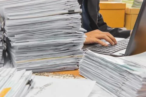 Documents on desk stack up high waiting to be managed Stock Photos
