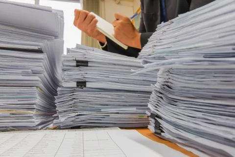 Documents on desk stack up high waiting to be managed Stock Photos