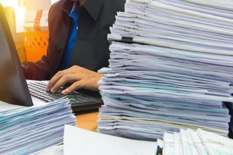 Documents on desk stack up high waiting to be managed Stock Photos