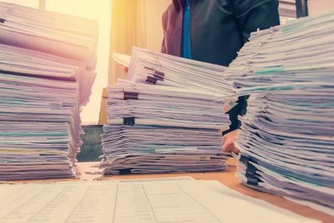 Documents on desk stack up high waiting to be managed 스톡 사진