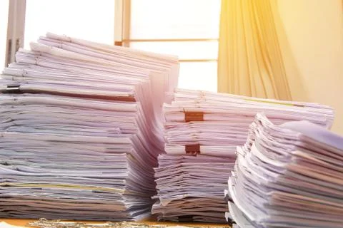 Documents on desk stack up high waiting to be managed Stock Photos