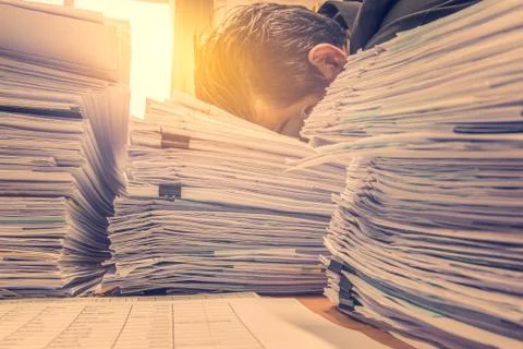 Documents on desk stack up high waiting to be managed 스톡 사진