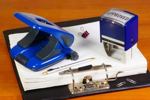 Documents in a folder, a hole punch and a seal. Stock Photos