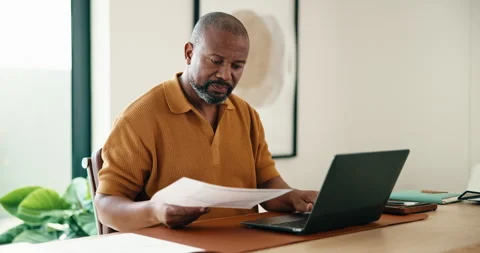 Documents, laptop and remote work with black man in home office for report, Stock Footage 337764079