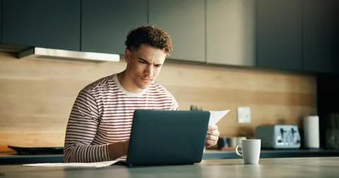 Documents, laptop and remote work with man in kitchen of home for problem s.. Stock Photos