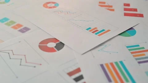 Documents with various charts and graphs are displayed on a flat surface, Видео 338304046