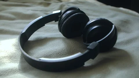 Dog sniffs headphones lying on the bedspread Stock Footage 256434116