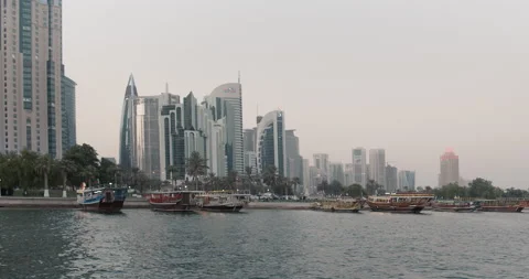 Doha, Qatar - Downtown skyscrapers and traditional boats from sea. Video stock 221871453