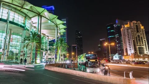 DOHA, QATAR - OCT 25, 2024: Night view of a lively street with palm trees, lit Stock Footage 289836182