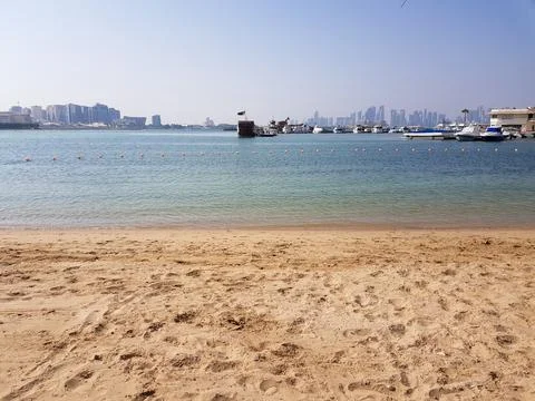 Doha, Qatar - Sandy beach with clear water, boats and city skyline in the backgr Fotos de archivo