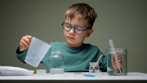 Doing experiments at home. Quarantine, stay at home. Boy with measuring cup at Stock Footage 127869100