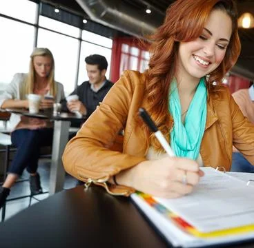 Doing her assignment on the go. A beautiful young woman sitting in a coffee shop Stock Photos