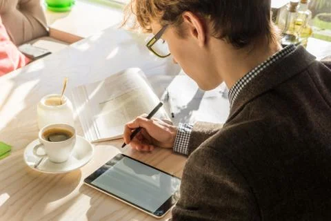Doing home assignment project at cafe during lunch. Young modern male teenage Stock Photos