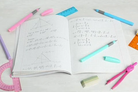 Doing homework. Notebook with math assignment and stationery on white desk,.. Stock Photos