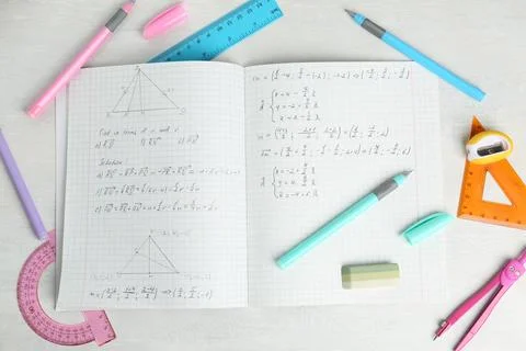 Doing homework. Notebook with math assignment and stationery on white desk,.. Stock Photos