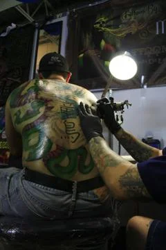 Doing a huge tattoo on his back Stock Photos