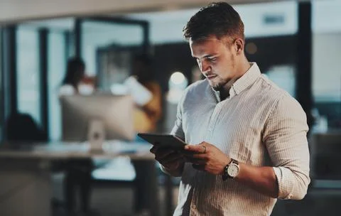 Doing it all with utmost efficiency. a young businessman using a digital tablet Stock Photos