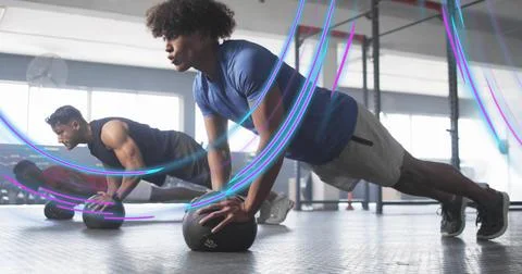 Doing push-ups man in athletic clothes balancing on medicine ball in gym room Fotos Stock
