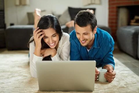 Doing some weekend blogging together. an affectionate young couple lying down on Stock Photos