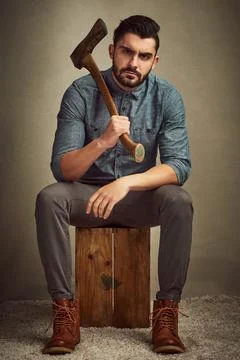 Doing strong in a dashing way. Studio shot of a young man posing with an axe  Stock Photos